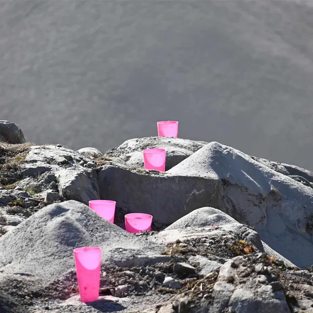 Rosa markører står plassert i borehull på fjell for å markere sprengningspunkter.