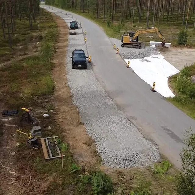 Dronebilde av veiarbeid der maskiner og biler beveger seg langs en vei under oppgradering.